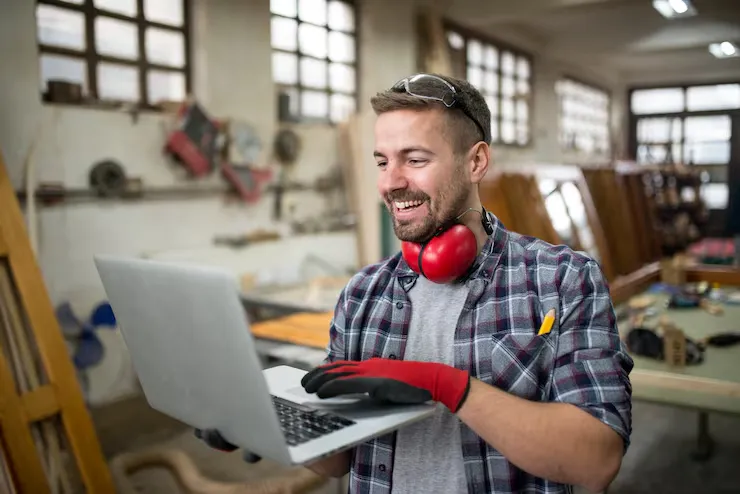 Freelancer with earmuffs working on a laptop in a workshop