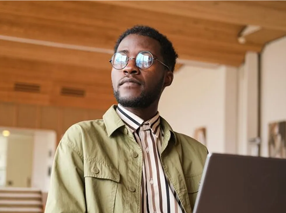 Gig worker in orange shirt focusing on laptop